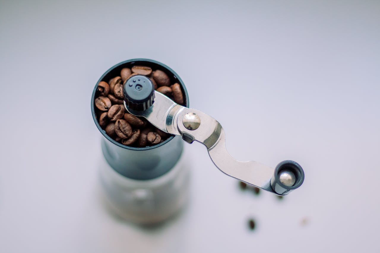 Top view of a manual coffee grinder filled with fresh coffee beans.
