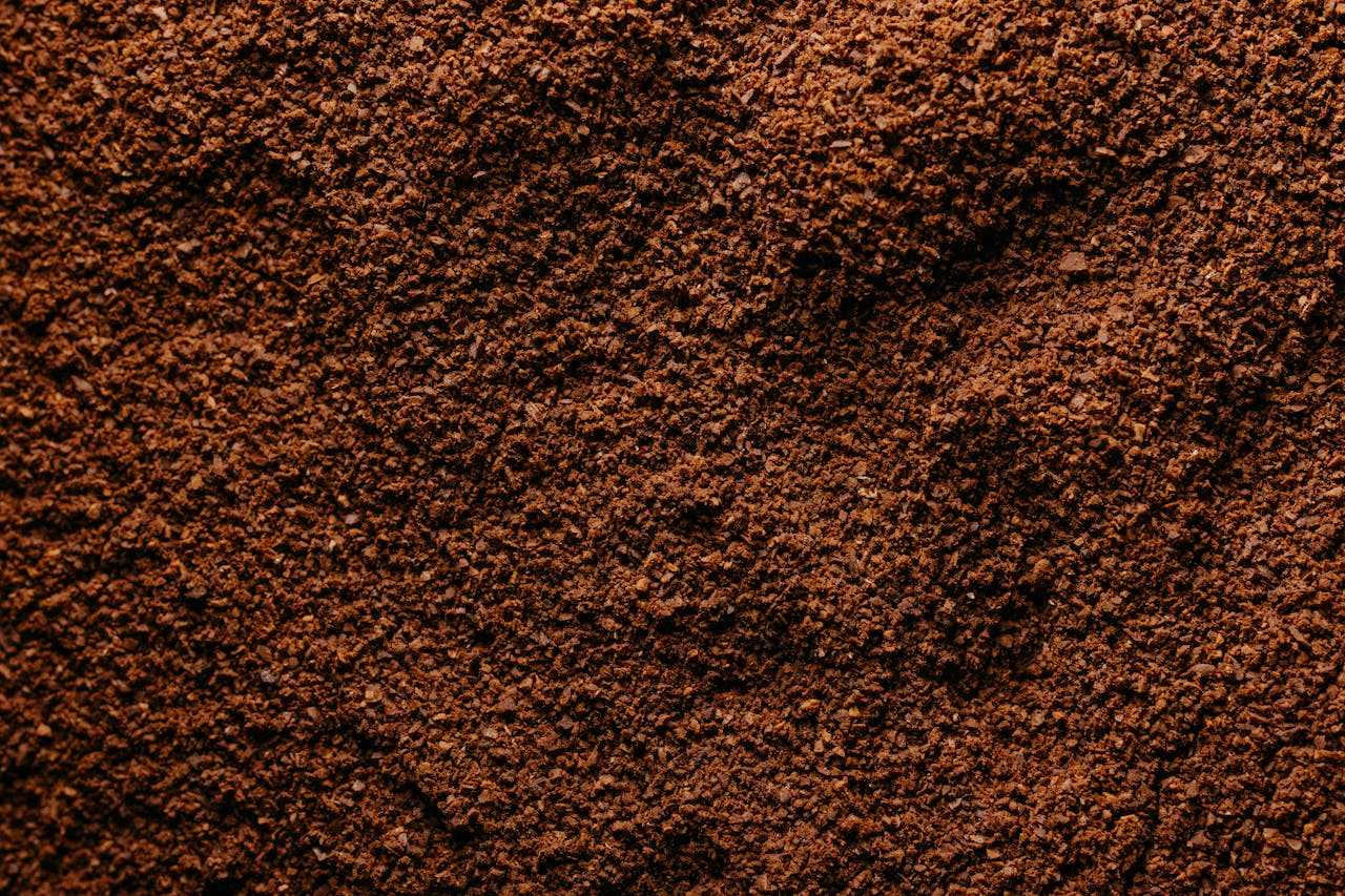 about-01 Detailed close-up image of freshly ground coffee showcasing rich brown texture.